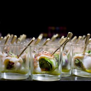 Stukje springrol met garnaal en koriander in rijstvel op prikker in amuse glas